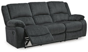 Ashley Furniture Draycoll reclining sofa with plush fabric and padded armrests, shown in an open reclining position.