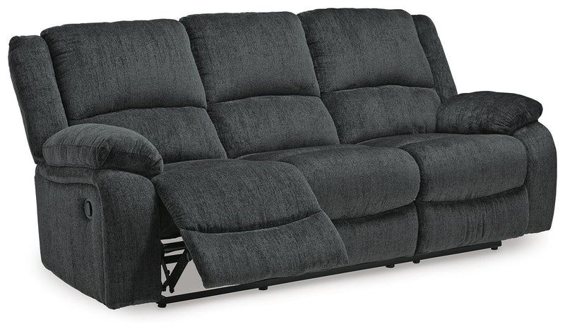 Ashley Furniture Draycoll reclining sofa with plush fabric and padded armrests, shown in an open reclining position.