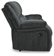 Ashley Furniture Draycoll reclining sofa with plush fabric and padded armrests, shown from the side in a modern living room setting.