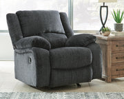 Ashley Furniture Draycoll recliner in beige fabric, showing a close-up of the cushioned armrest and plush seating.