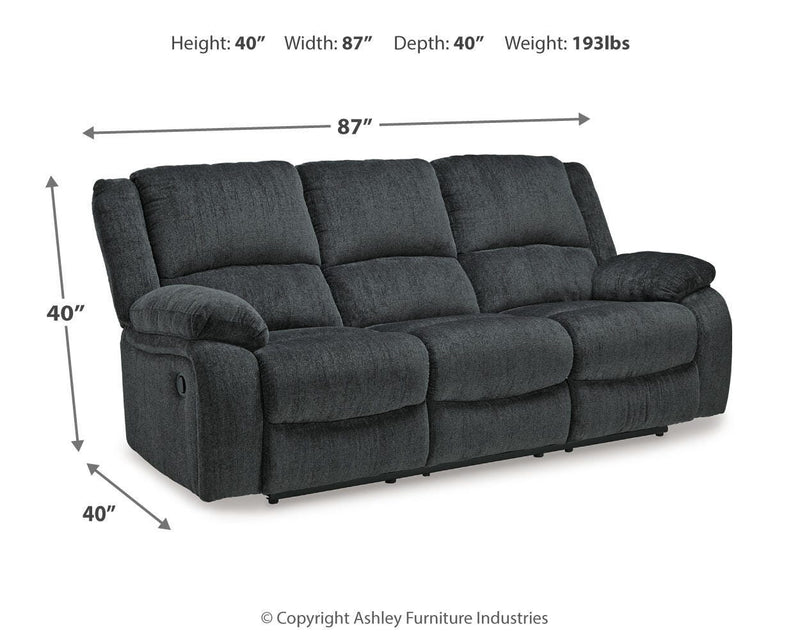Ashley Furniture Draycoll reclining sofa with plush cushions and a dark fabric finish, designed for comfortable lounging.