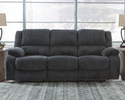 Ashley Furniture Draycoll reclining sofa shown in open position with plush cushions and dark upholstery in a modern living room setting.