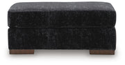 Ashley Furniture Whitmore Manor Ottoman showing a plush, beige upholstered top with wooden legs and classic design.