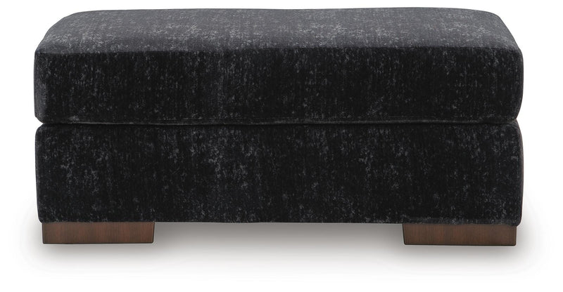 Ashley Furniture Whitmore Manor Ottoman showing a plush, beige upholstered top with wooden legs and classic design.