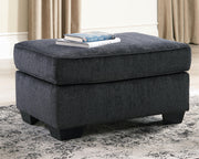 Ashley Furniture Altari Ottoman with cushioned top and wooden legs, beige fabric upholstery, and compact rectangular design.