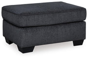 Ashley Furniture Altari Ottoman in soft gray fabric with tufted top and wooden block legs, perfect for living room or bedroom decor.