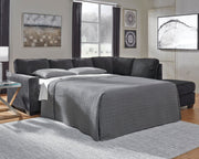 Ashley Furniture Altari Sleeper Sectional with Chaise, beige fabric, with plush cushions and a built-in sleeping area, shown in a modern living room.