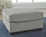 Ashley Furniture Altari oversized accent ottoman with fabric upholstery and wooden legs, shown in a cozy living room setting.