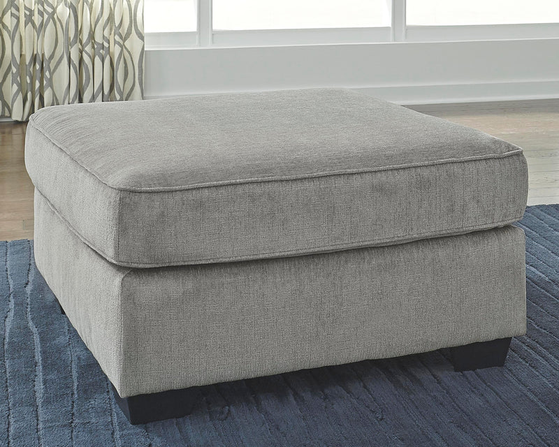 Ashley Furniture Altari oversized accent ottoman with fabric upholstery and wooden legs, shown in a cozy living room setting.