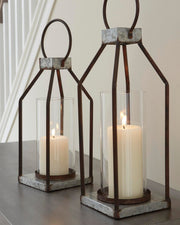 Set of two Diedrick Lantern candle holders by Ashley Furniture with glass panels and metal frames on a wooden surface.