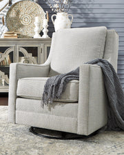 Ashley Furniture Kambria swivel glider accent chair with plush upholstery and wooden legs, shown in a cozy living room setting.
