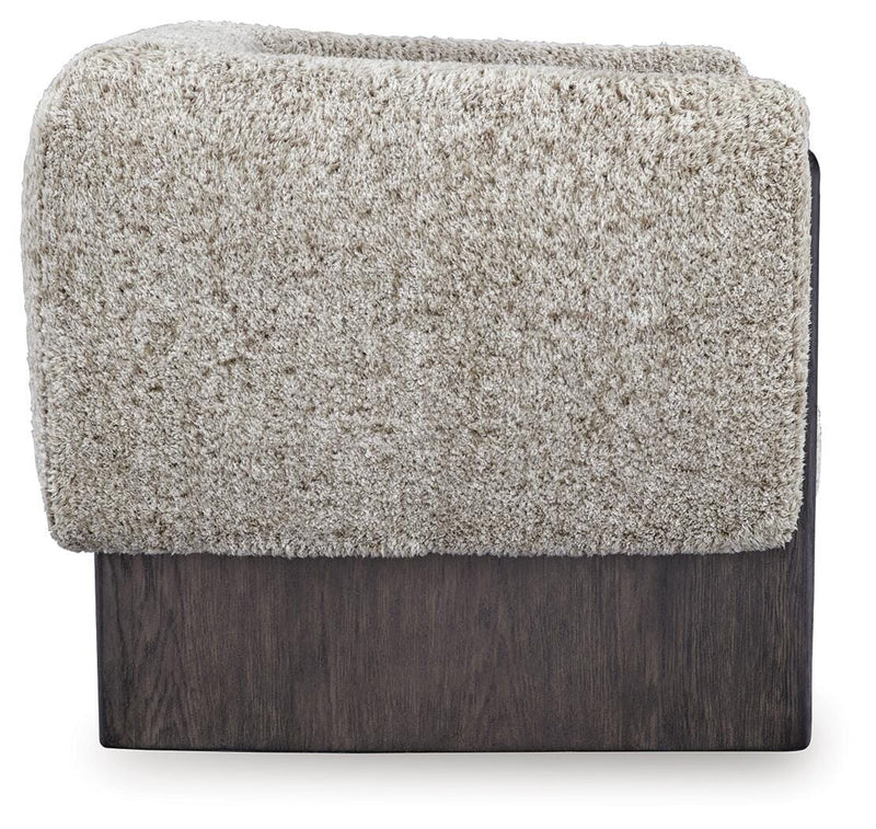 Ashley Furniture Olethea accent chair with plush fabric and wooden legs, shown from a side angle in a modern living room setting.