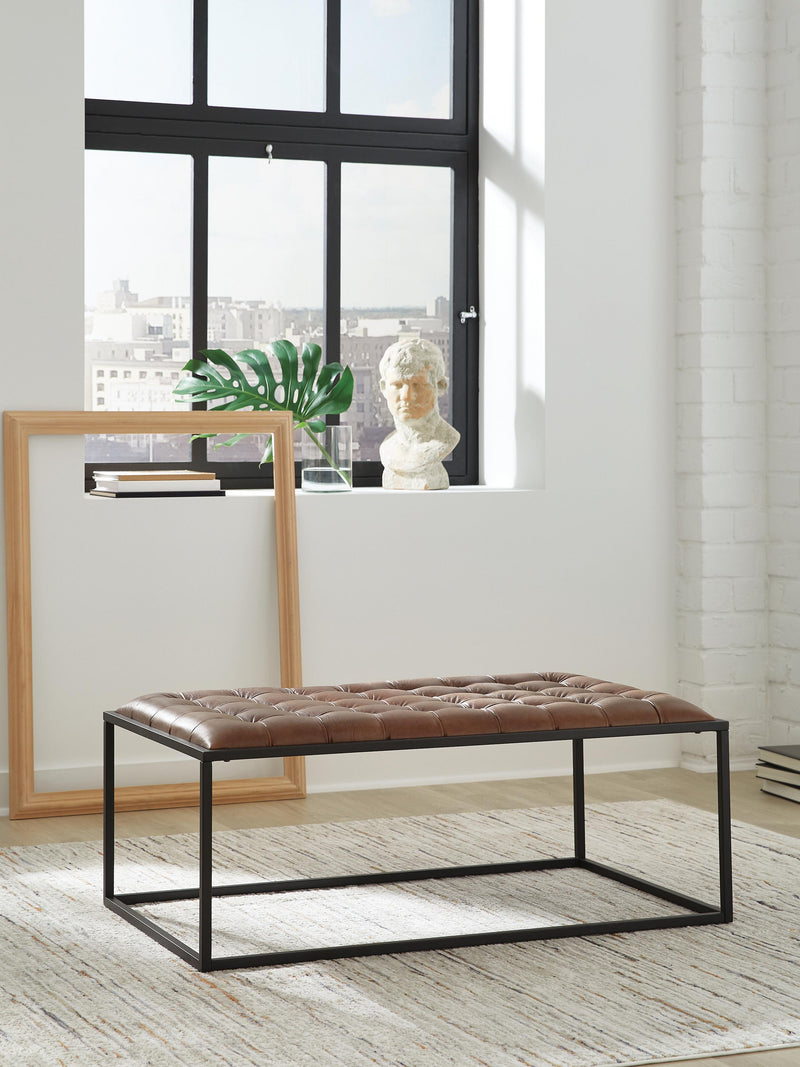 Ashley Furniture Junsor coffee table ottoman with a cushioned top and wooden legs, perfect for living room decor.