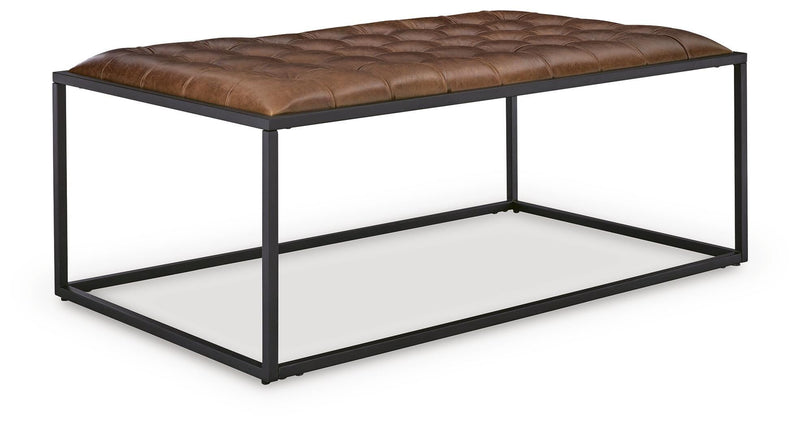 Ashley Furniture Junsor coffee table ottoman with plush fabric and wooden legs, shown from an angled view.