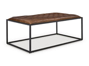 Ashley Furniture Junsor coffee table ottoman with a plush upholstered top and wooden legs, shown from an angled side view.