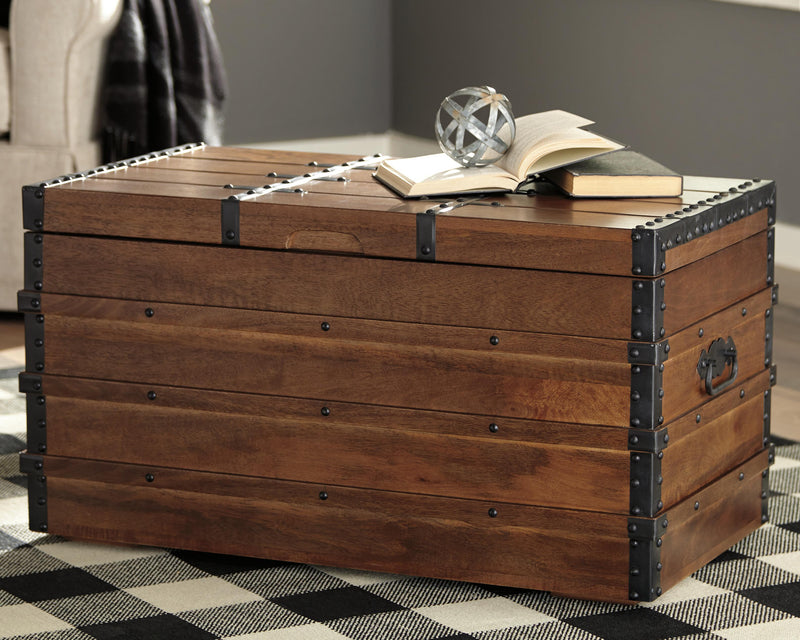 Ashley Furniture Kettleby Storage Trunk in light wood finish, showing a sturdy trunk with metal accents and spacious interior.