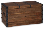 Ashley Furniture Kettleby Storage Trunk showing a closed wooden trunk with metal accents and a sturdy rectangular design.