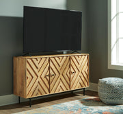 Ashley Furniture Cadewick accent cabinet with wood finish and decorative hardware, shown in a stylish living room setting.