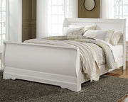 Ashley Furniture Anarasia Bed with upholstered headboard and wood frame, shown in a cozy bedroom setting.