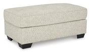 Ashley Furniture Heartcort Ottoman featuring a plush upholstered top and wooden legs for versatile home decor and seating.