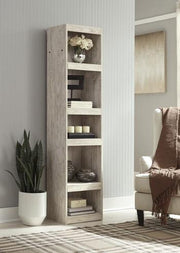 Willowton Pier media tower by Ashley Furniture, showcasing a modern wooden design with open shelving and storage compartments.