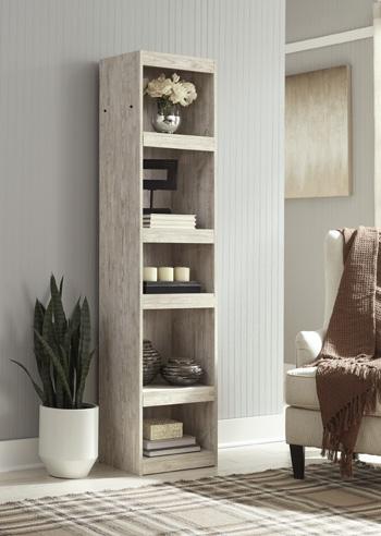 Willowton Pier media tower by Ashley Furniture, showcasing a modern wooden design with open shelving and storage compartments.