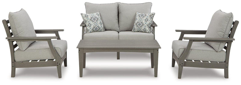 Ashley Furniture Visola outdoor loveseat conversation set with cushioned seats and matching coffee table in a backyard setting