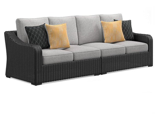 Ashley Furniture Beachcroft 2-piece outdoor loveseat sectional with cushions, featuring woven rattan design and comfortable seating.