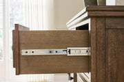 Ashley Furniture Sturlayne dresser with attached mirror showcasing a modern wood finish and sleek hardware in a contemporary bedroom setting.