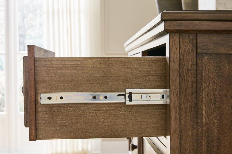 Ashley Furniture Sturlayne dresser with attached mirror showcasing a modern wood finish and sleek hardware in a contemporary bedroom setting.