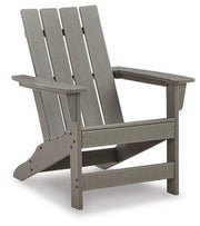 Outdoor Ashley Furniture Visola Adirondack Chair with matching end table in a garden setting, perfect for outdoor relaxing.