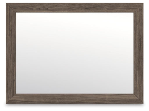 Ashley Furniture Kendanport bedroom mirror with a sleek, framed design, shown hanging on a wall in a modern bedroom setting.