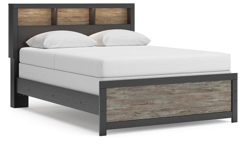 Ashley Furniture Broachmyn Bed with a dark wood finish, featuring a tall, paneled headboard and sturdy frame in a well-lit bedroom setting.