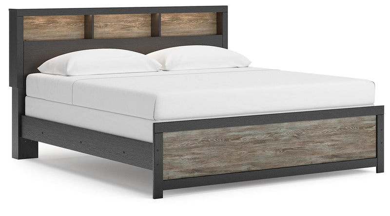 Ashley Furniture Broachmyn Bed with upholstered headboard and wood frame, shown from a side angle in a well-lit bedroom setting.