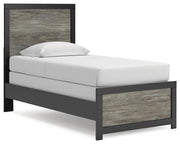 Ashley Furniture Broachmyn Bed shown from a side angle with a wooden headboard and frame in a cozy bedroom setting.