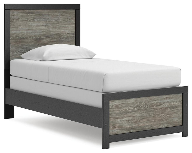 Ashley Furniture Broachmyn Bed shown from a side angle with a wooden headboard and frame in a cozy bedroom setting.