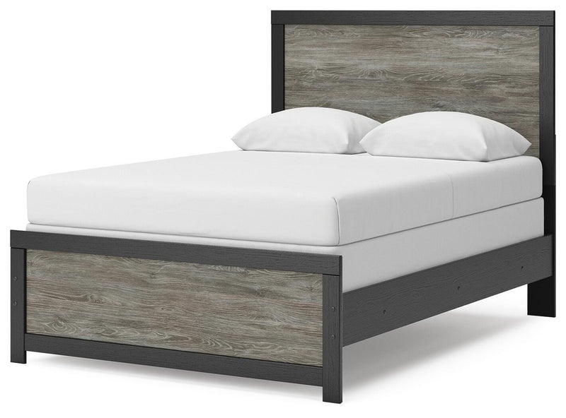 Ashley Furniture Broachmyn Bed with a stylish wooden frame and upholstered headboard, shown from an angled side view.