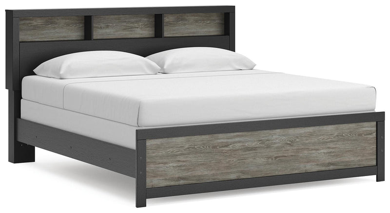 Ashley Furniture Broachmyn Bed with a stylish upholstered headboard and wooden frame, shown from a side angle in a well-lit room.