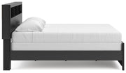 Ashley Furniture Broachmyn Bed with a wooden frame and upholstered headboard, shown from a side angle in a bedroom setting.