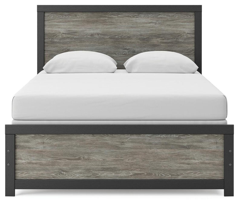 Ashley Furniture Broachmyn Bed with a headboard featuring detailed woodwork and a classic design in a cozy bedroom setting.