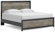 Ashley Furniture Broachmyn Bed with a wooden headboard and frame, shown from a side angle in a bedroom setting.