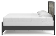 Ashley Furniture Broachmyn Bed with a wooden frame and headboard, shown from a side angle in a modern bedroom setting.
