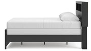 Ashley Furniture Broachmyn Bed with a wooden frame and headboard, shown from a side angle in a modern bedroom setting.