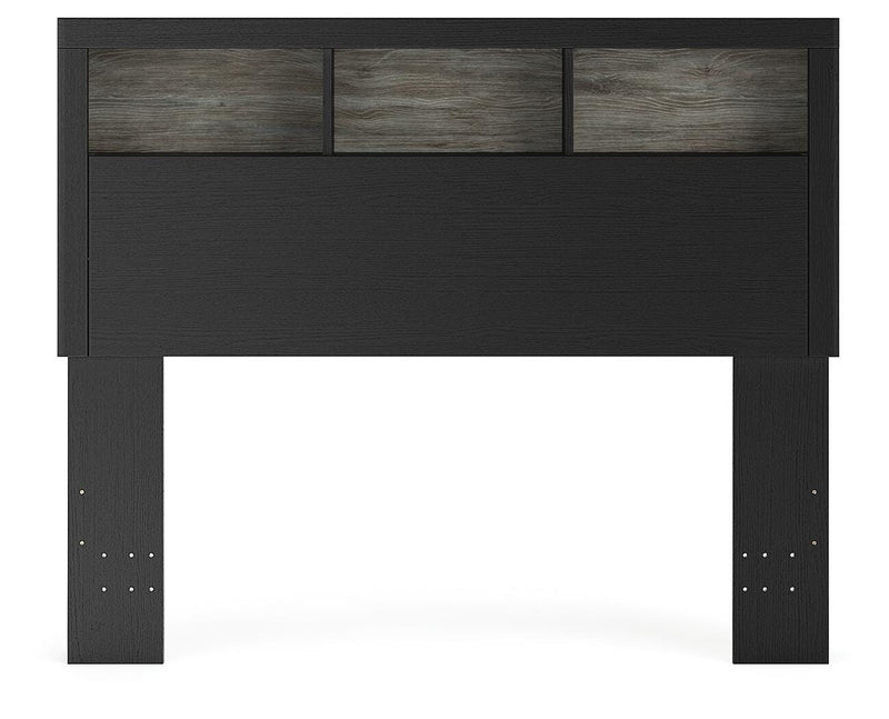 Ashley Furniture Broachmyn Bed with a headboard featuring detailed wood carvings and a dark finish, shown in a stylish bedroom setting.