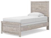 Ashley Furniture Broachmyn Bed with a modern wooden frame and angled headboard, shown from a side angle in a bedroom setting.