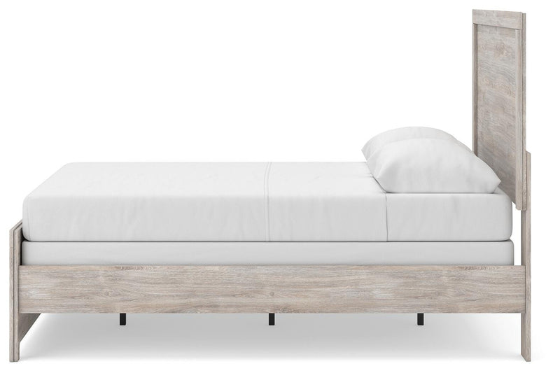 Ashley Furniture Broachmyn bed with a wooden frame and headboard, shown from a side angle in a bedroom setting.