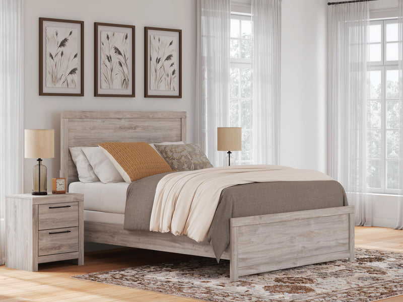 Ashley Furniture Broachmyn Bed with tufted headboard and wooden frame, shown in a cozy bedroom setting.