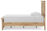 Ashley Furniture Makidern Bed with a wooden frame and headboard, shown from a side angle in a well-lit bedroom setting.