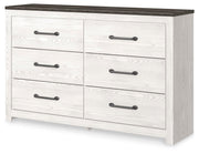 Ashley Furniture Gerridan Dresser with multiple drawers, shown from an angled side view in a modern bedroom setting.