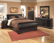 Ashley Furniture Huey Vineyard Bed with a wooden frame and upholstered headboard, shown in a cozy bedroom setting.